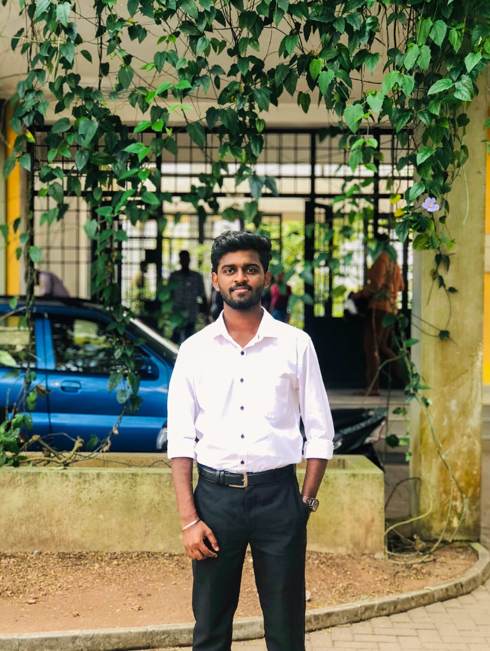 Portrait of Niroshan Chandrasekaran, Committee Member of the Tamil Student Association, smiling and wearing formal attire, standing in a university or event setting. If visible, text in the image: Niroshan Chandrasekaran Committee Member. The atmosphere is welcoming and professional.